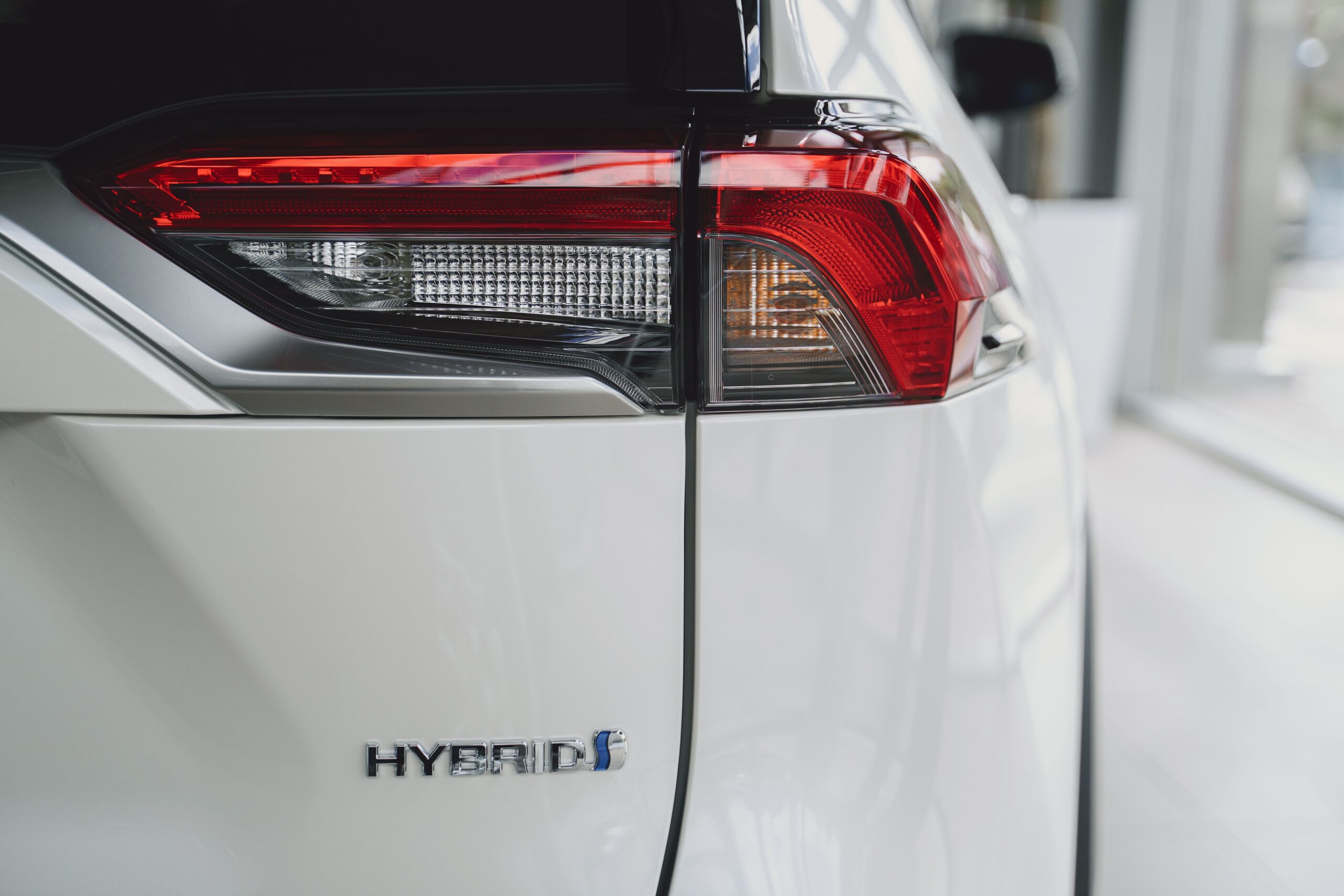 Detalhe da traseira de um SUV híbrido moderno com identificação da tecnologia híbrida.