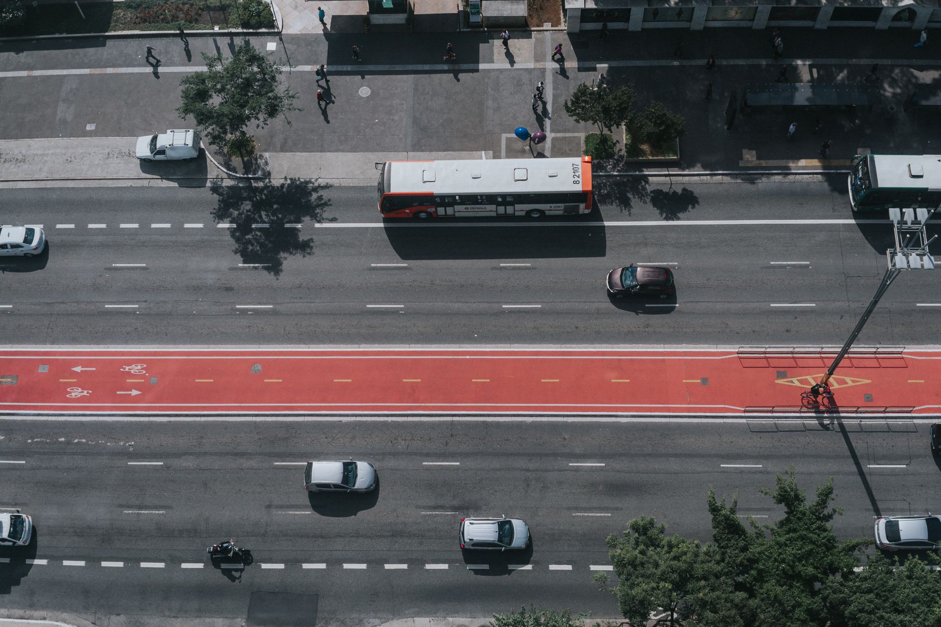 Vista aérea de via urbana com ciclofaixa em vermelho no centro da pista.