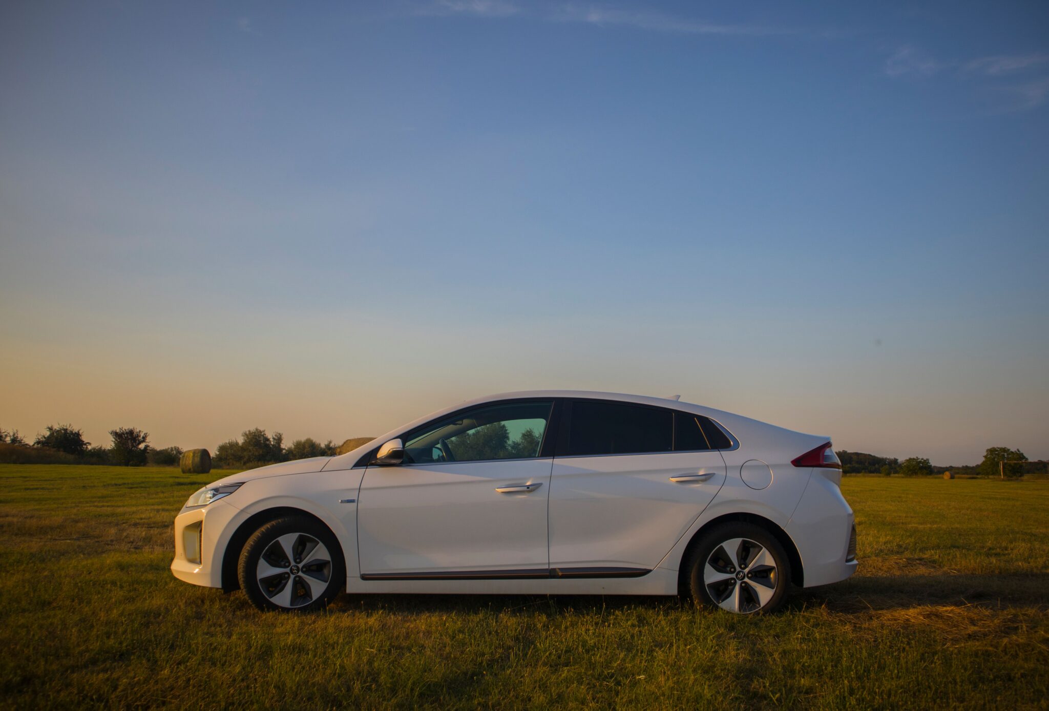 Carro híbrido branco em uma estrada rural